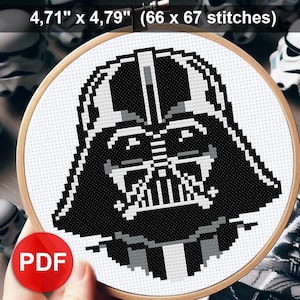 Puede incluir: Un patrón de punto de cruz en blanco y negro de la cara de Darth Vader sobre un fondo blanco. El patrón está en un aro de bordado de madera. El texto "4.71" x 4.79" (66 x 67 puntos)" está en la parte superior de la imagen. El texto "PDF" está en un cuadrado rojo en la parte inferior izquierda de la imagen.