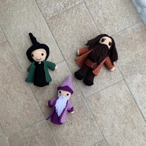 Può includere: Tre figure all'uncinetto, una con un cappello e una tunica verdi, una con un cappello e una tunica viola e l'ultima con una barba marrone e una tunica arancione.