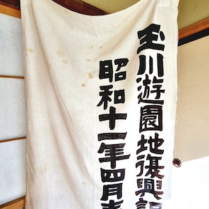 以下が含まれることがあります： 「全川國生地業會 昭和四年四月」と黒文字で書かれた白い布の旗。これは「全川国生地業会 昭和四年四月」と訳されます。
