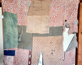 May include: A patchwork quilt made from different fabrics in shades of pink, green, black, and white. The quilt is made up of squares and rectangles of fabric sewn together. The quilt is torn in some places, revealing the fabric underneath.