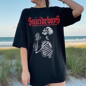 May include: Black t-shirt with a graphic of a praying skeleton and the text "Suicideboys$ The number you have dialed is not in service."