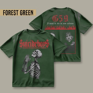 May include: Forest green t-shirt with a skeleton praying on the front and the text "Suicideboy$ THE MOMENT YOU WERE BORN YOU WERE ALREADY IN HELL" and on the back the text "659 I want to die in new orleans" with flames.