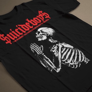 May include: Black t-shirt with a red graphic of a skeleton praying with the text "Suicideboys" and the phrase "The number you have dialed is not in service".