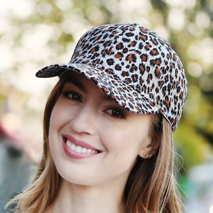 May include: A brown and white leopard print baseball cap with a curved brim.