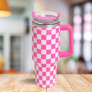 Puede incluir: Taza de viaje de acero inoxidable rosa con un patrón a cuadros y una tapa con una pajita. La taza tiene un asa.