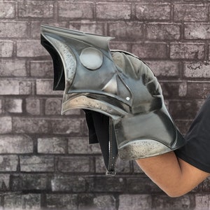 Op de afbeelding: Een zwarte metalen harnas handschoen met een getextureerd oppervlak en een puntig ontwerp. De handschoen wordt gedragen op de arm van een persoon.