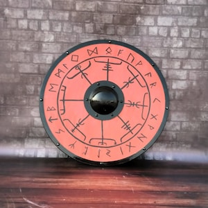 Könnte beinhalten: Ein runder, roter Schild mit schwarzem Rand und Runen. Der Schild hat eine schwarze Mitte mit einer kreisförmigen, schwarzen, reflektierenden Oberfläche.