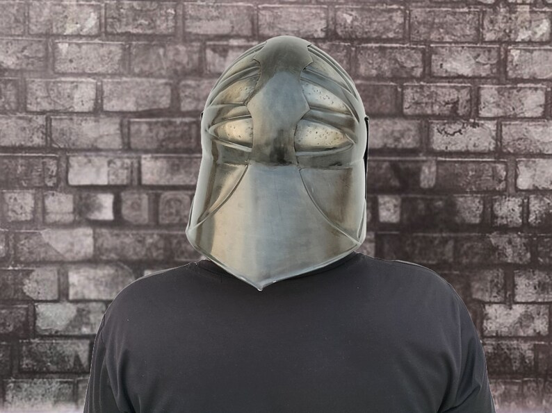 Op de afbeelding: Een persoon draagt ​​een zwarte helm met een gezichtsbeschermer en een zwart shirt.