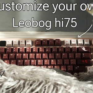 Könnte beinhalten: Eine personalisierte Leobog hi75 Tastatur mit braunen Tastenkappen und weißen Akzenten. Die Tastatur hat ein Geister-Symbol auf der Escape-Taste und einen roten Schädel auf der Backspace-Taste.