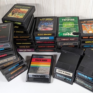 May include: A collection of vintage Atari video game cartridges, including titles like "Dodge 'em", "Defender", "Combat", "Championship Soccer", "Breakout", "Bowling", "Basketball", "Air Sea Battle", "Pele's Soccer", "Slot Racers", "Skiing", "Tennis", "Target Fun", "Street Racer", "Yars' Revenge", "Warlords", "Video Pinball", "Trick Shot", "Lock 'n' Chase", "Space Attack", "Astroblast", and "Armor Ambush".