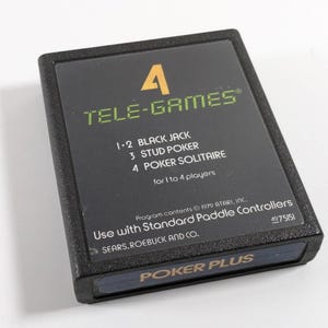 May include: A black Atari game cartridge for the Atari 400 and 800 computers. The cartridge is labeled "Poker Plus" and features four poker games: Black Jack, Stud Poker, Poker Solitaire, and a four-player poker game. The cartridge is labeled "Use with Standard Paddle Controllers" and "Sears, Roebuck and Co."