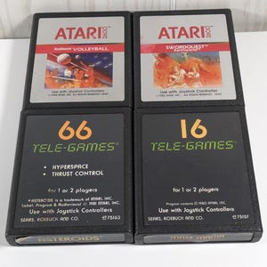 May include: Four vintage Atari and Tele-Games video game cartridges. Two Atari cartridges feature the games "Volleyball" and "Swordquest Earthworld." The Tele-Games cartridges display "66 Tele-Games" and "16 Tele-Games."
