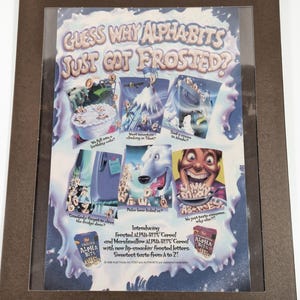 May include: A colorful cereal box advertises Frosted Alpha-Bits cereal with marshmallow Alpha-Bits. The ad features a polar bear and a cartoon character with a surprised expression. The text on the box reads "Guess why Alpha-Bits just got frosted?" and "Introducing Frosted Alpha-Bits Cereal and Marshmallow Alpha-Bits Cereal with new lip-smacking frosted letters. Sweetest taste from A to Z!"