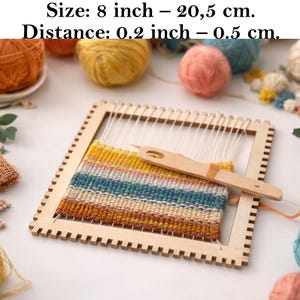 Può includere: Un telaio in legno con un campione tessuto colorato. Il telaio è quadrato, di circa 20,3 cm di dimensioni, con un telaio dentellato e fili bianchi. Un ago di legno è inserito nel tessuto tessuto. Il campione tessuto presenta strisce gialle, blu e marroni.