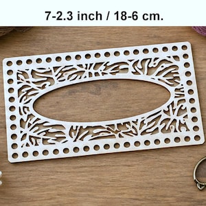 May include: A rectangular light-colored wooden base with a central oval cutout and intricate laser-cut branch patterns. The perimeter features evenly spaced holes for stitching. The text 7-2.3 inch is printed above the object.
