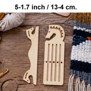 Puede incluir: Dos herramientas de tejido de madera clara con cabezas en forma de caballo y detalles grabados. Una herramienta es una pieza larga y delgada, y la otra es un peine de telar rectangular con ranuras verticales y cinco pequeños agujeros. Mide 13-4 cm.