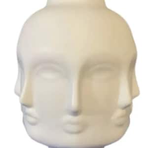Può includere: Vaso in ceramica bianca con quattro volti stilizzati scolpiti sul davanti. Il vaso è un design moderno e astratto.
