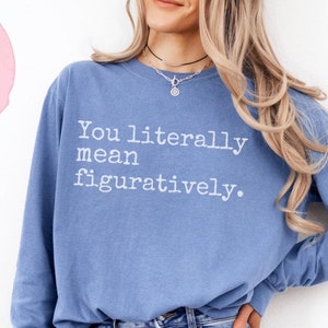 May include: A blue long-sleeved sweatshirt with the text "You literally mean figuratively." printed in white on the front.