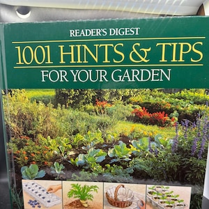 May include: A green book titled "1001 Hints & Tips For Your Garden" by Reader's Digest. The cover features a lush garden scene with various plants and flowers. The bottom of the cover shows three illustrations of gardening techniques.