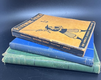 May include: A stack of three vintage hardcover books. The top book is brown with black text that reads "Reviewing French 1st Year". The middle book is blue with black text that reads "Reviewing French First Year AMSCO". The bottom book is green with black text that reads "Britannicus Racine".
