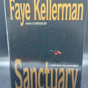 Könnte beinhalten: Ein Hardcover-Buch mit dem Titel "Sanctuary" von Faye Kellerman. Das Buch hat einen schwarzen Einband mit goldener Schrift und einem kleinen Bild einer Pistole. Der Name des Autors und der Titel sind deutlich sichtbar.