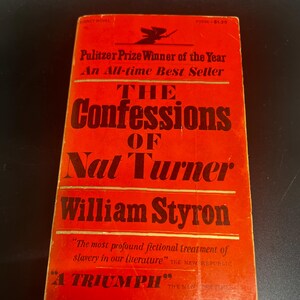 May include: A red paperback book cover with the title "The Confessions of Nat Turner" by William Styron. The book is a Pulitzer Prize winner and an all-time best seller. The cover features a small illustration of a witch.