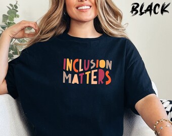 May include: A black t-shirt with the text "INCLUSION MATTERS" in colorful letters.