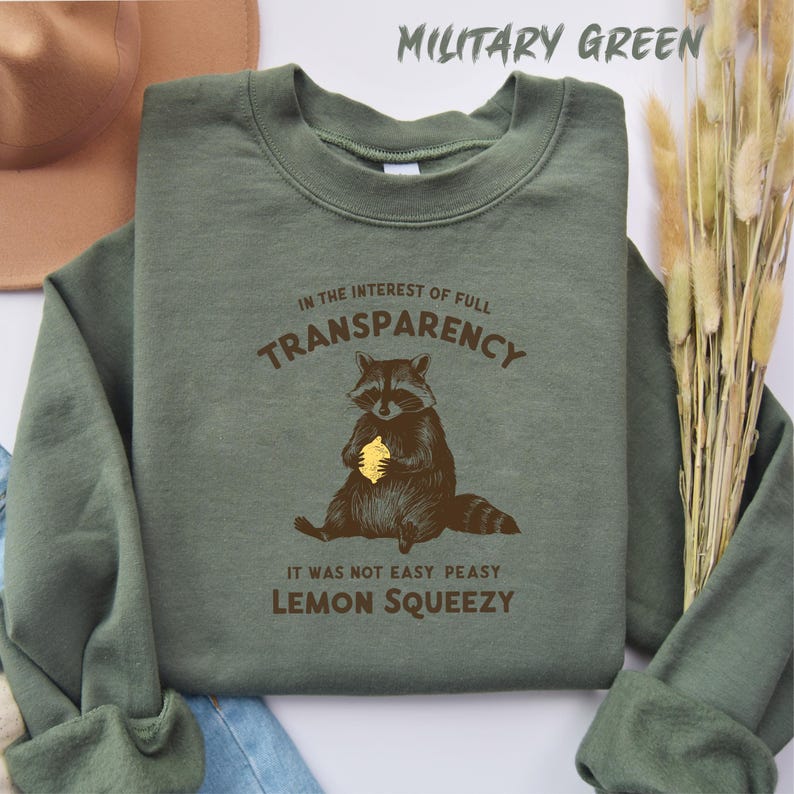 May include: A green sweatshirt with a raccoon holding a lemon and the text "In the interest of full transparency it was not easy peasy lemon squeezy".