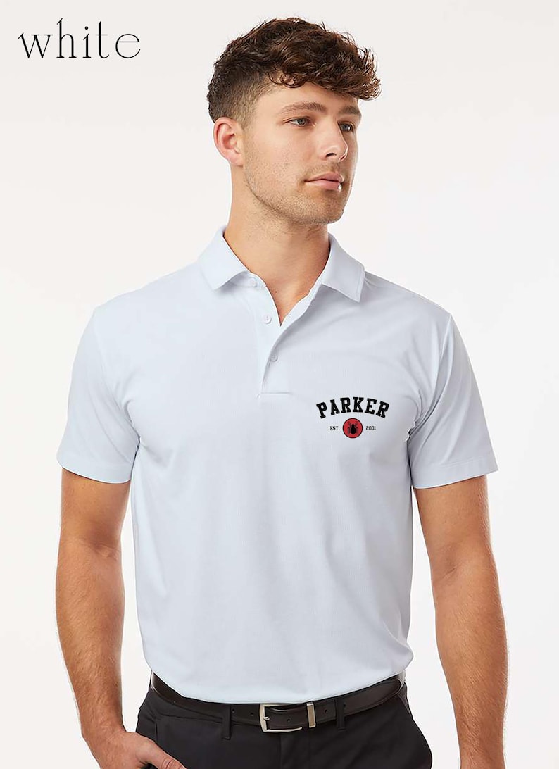 Puede incluir: Polo blanco con cuello y mangas cortas. La camisa presenta un logotipo negro y rojo que dice "PARKER" con "EST. 2023". El modelo lleva pantalones negros y un cintur&oacute;n negro.