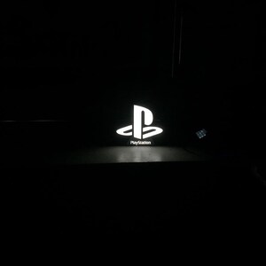 May include: A white PlayStation logo with the word "PlayStation" underneath it.