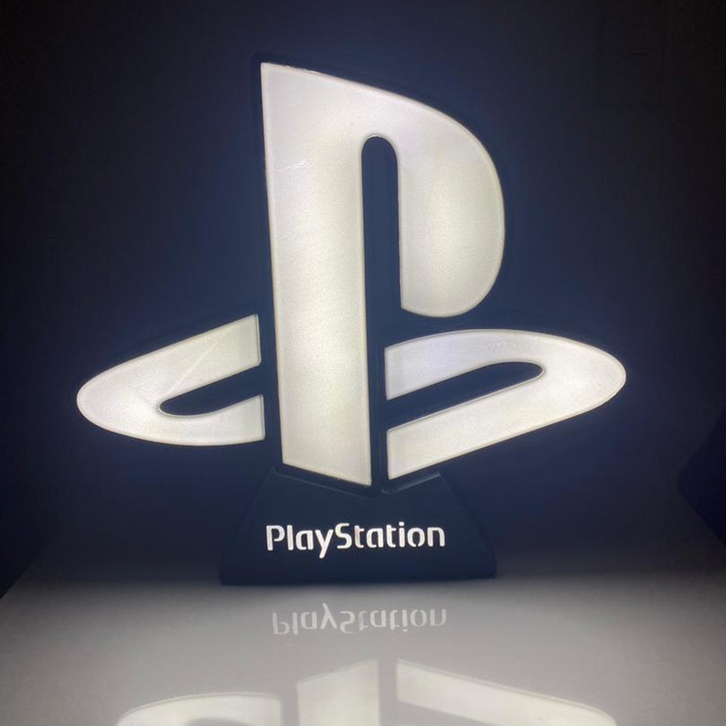 May include: A white PlayStation logo light with a black base. The logo is illuminated and the base has the word "PlayStation" printed on it.