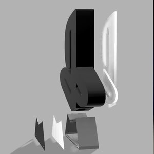 May include: A black and white PlayStation logo made of multiple pieces. The logo is made of a black base, a white outline, and a black top piece. The logo is sitting on a gray surface.