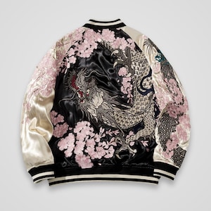 May include: A black and cream satin bomber jacket featuring an intricate embroidered design of a large dragon surrounded by pink cherry blossoms. The jacket has a ribbed collar, cuffs, and hem with black and white stripes, and long sleeves.