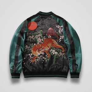 May include: A black and teal satin bomber jacket featuring an intricate back embroidery of a tiger, bamboo stalks, cherry blossoms, a mountain peak, and a red sun. The jacket has long sleeves with black stripes, a ribbed collar, and ribbed cuffs.