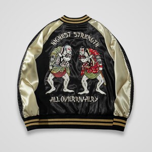 Könnte beinhalten: Eine schwarze und cremefarbene Satin-Bomberjacke mit einer gestickten Rückseite, die zwei Figuren in traditioneller Kleidung zeigt, die sich gegenüberstehen. Der Text HIGHEST STRENGTH und ALL OVER RIVALRY ist in Weiß eingestickt.