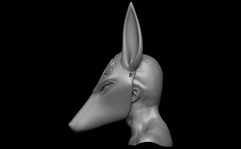 May include: A gray Anubis mask, featuring a canine head with long ears and detailed facial features. The mask is sculpted with intricate patterns above the eye and is designed to fit over the face and head.