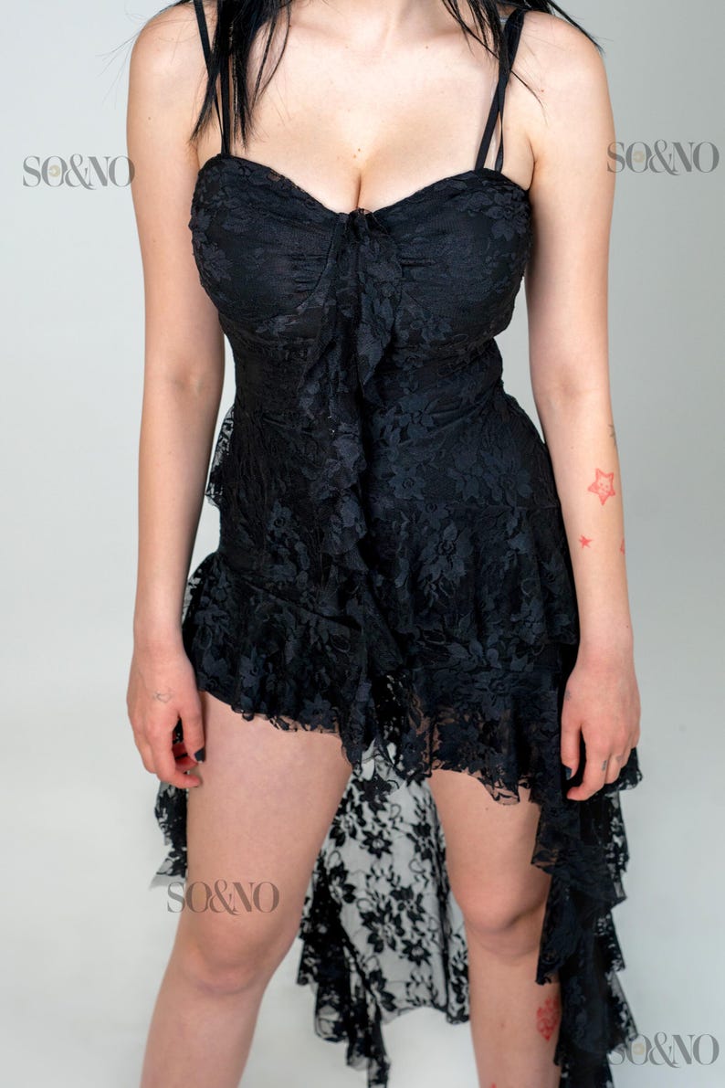 May include: A black lace dress with a high-low hemline and a sweetheart neckline. The dress has a ruffled skirt and a fitted bodice. The dress is adorned with delicate lace details.