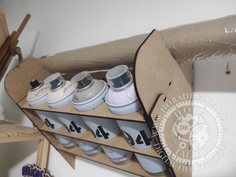 Puede incluir: Un organizador de botes de pintura en aerosol de madera con m&uacute;ltiples compartimentos. El organizador contiene varios botes de pintura en aerosol, cada uno etiquetado con el n&uacute;mero "4". Los botes son blancos con n&uacute;meros negros. El organizador es de madera marr&oacute;n claro.