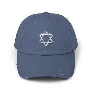 Puede incluir: Una gorra de béisbol azul desgastada con un diseño bordado blanco de una estrella de seis puntas hecha de código binario.