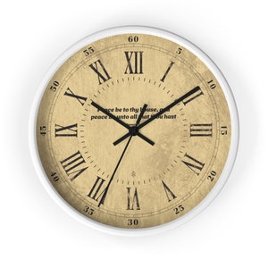 Può includere: Un orologio rotondo bianco con numeri romani neri e lancette nere. Il quadrante dell'orologio ha una texture di carta vintage invecchiata con una citazione in testo nero: "Peace be to thy house, and peace be unto all that thou hast."