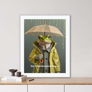 May include: A green frog wearing a yellow raincoat and holding an orange umbrella stands under a clear umbrella in a rainy setting. The text "Der Schlechtwetterfrosch" is written below the frog.