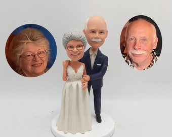 May include: A wedding cake topper featuring a bride and groom in a realistic style. The bride is wearing a white dress with lace detailing and the groom is wearing a dark blue suit. The couple is smiling and holding hands.