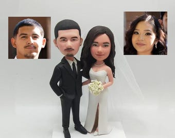 May include: A wedding cake topper featuring a bride and groom in a caricature style. The bride is wearing a white dress with a veil and the groom is wearing a black suit. The couple is holding a bouquet of white flowers.