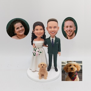 Op de afbeelding: Een bruidstaarttopper met een bruid en bruidegom in cartoon-stijl, met een kleine hond voor hen. De bruid draagt een witte jurk en de bruidegom draagt een donkergroen pak. De hond is bruin en wit.