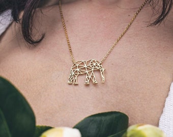 May include: A gold necklace with a geometric elephant pendant. The pendant is made of thin metal and has a delicate, intricate design.