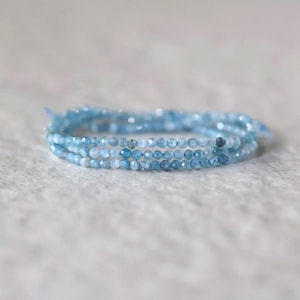Puede incluir: Una pulsera de m&uacute;ltiples hilos compuesta por peque&ntilde;as cuentas de piedras preciosas facetadas de color azul claro. Las cuentas exhiben una calidad transl&uacute;cida con tonos que var&iacute;an de azul p&aacute;lido a medio, dispuestas en forma circular con una textura delicada.