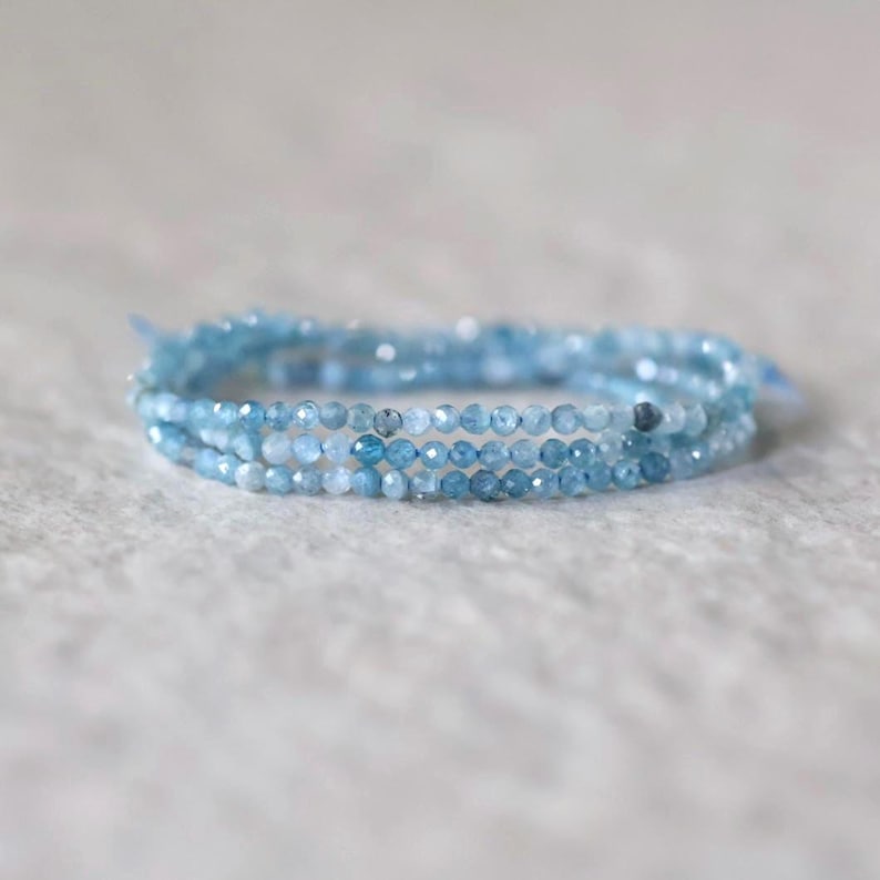 Puede incluir: Una pulsera de m&uacute;ltiples hilos compuesta por peque&ntilde;as cuentas de piedras preciosas facetadas de color azul claro. Las cuentas exhiben una calidad transl&uacute;cida con tonos que var&iacute;an de azul p&aacute;lido a medio, dispuestas en forma circular con una textura delicada.