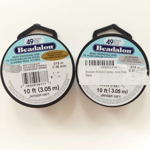 May include: Two spools of Beadalon bead stringing wire. One spool is 24K gold plated, and the other is silver plated. Each spool contains 10 ft (3.05 m) of .015 in (0.38 mm) wire. The packaging includes text in English, French, and Spanish.