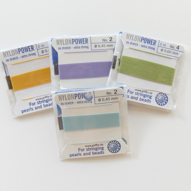 May include: Four spools of nylon cord in various colors: yellow, lavender, light green, and teal. Each spool is packaged in a clear plastic wrapper with white labels that read "NYLONPOWER" and "For stringing pearls and beads."