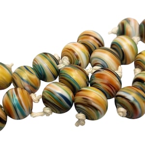 May include: A strand of colorful glass beads. Each bead is round with a swirled pattern of yellow, brown, teal, and white. The beads are strung together with white string, creating a decorative accessory.